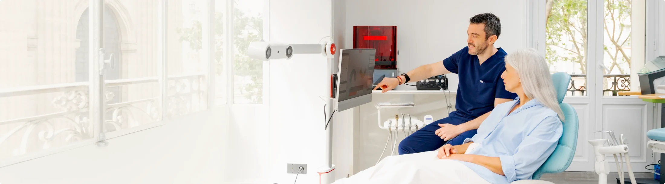 Chirurgien-dentiste à son poste de travail numérique, patiente installée au fauteuil